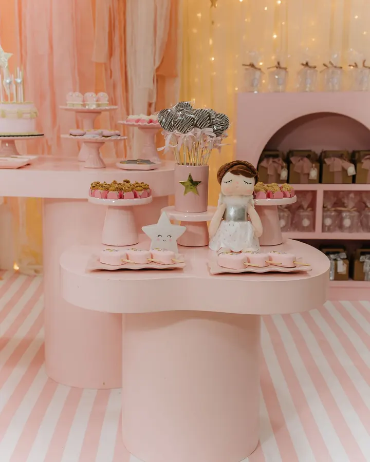 Mesas rosa com boneca de pano e doceiras