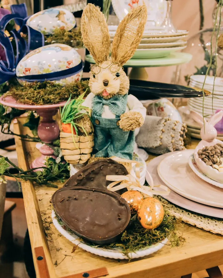 Coelho de palha com ovo de chocolate na mesa